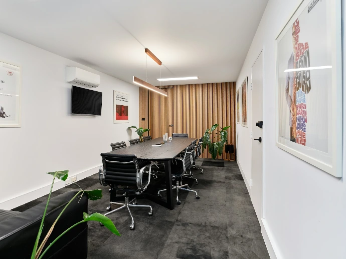 A modern meeting room with long table and chairs.